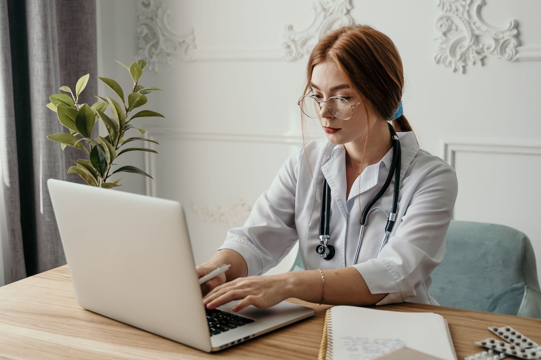 Dokter membaca panduan sistem informasi klinik dan rekam medis elektronik melalui laptop